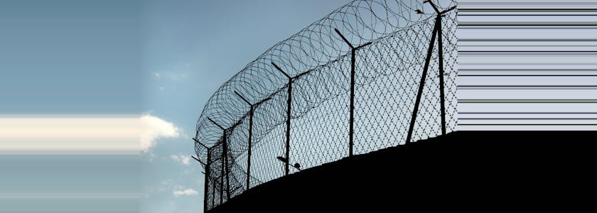 Silhouette of concertina barbed wire on a prison fence