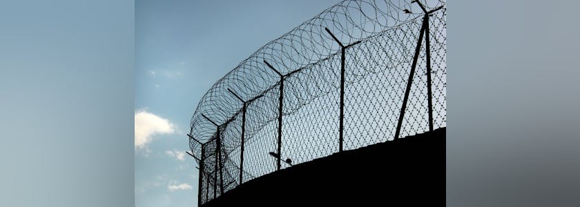 Silhouette of concertina barbed wire on a prison fence