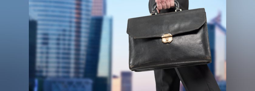 Businessman holding a briefcase with office buildings in background