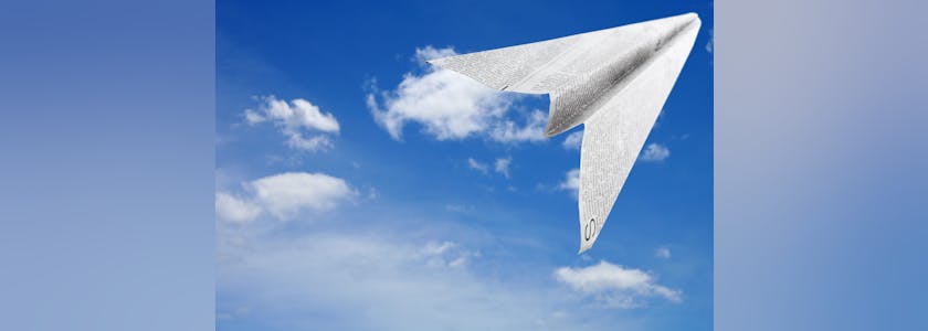 avion de papier en papier journal en train de voler sur fond de ciel bleu