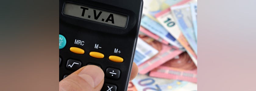 Photo d'une calculatrice avec indiqué sur l'écran TVA sur fond de billets euros