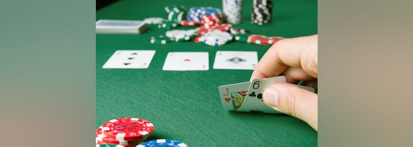 Un joueur regarde ses cartes sur une table de pocker
