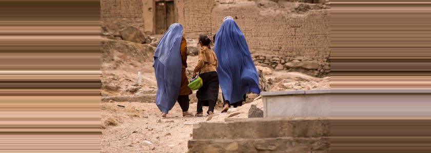 Girls and women in burqas walk through a graveyard near Kabul, Afghanistan