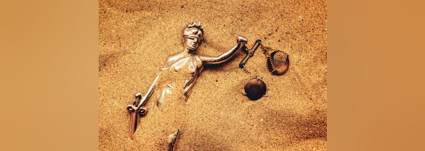 Statue of lady Justice buried in sand