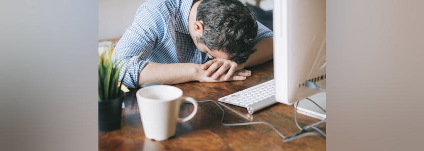 Tired office worker sleeping on front of his workstation