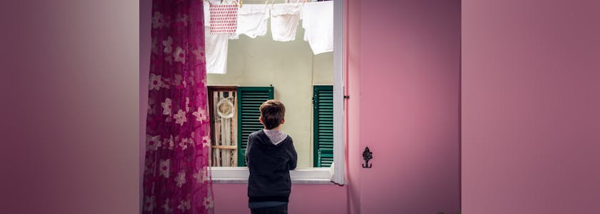 petit garçon devant une fenêtre dans une chambre colorée