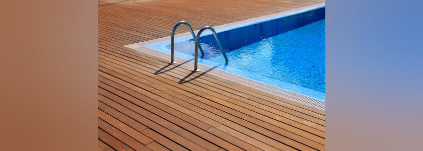 blue swimming pool with teak wood flooring