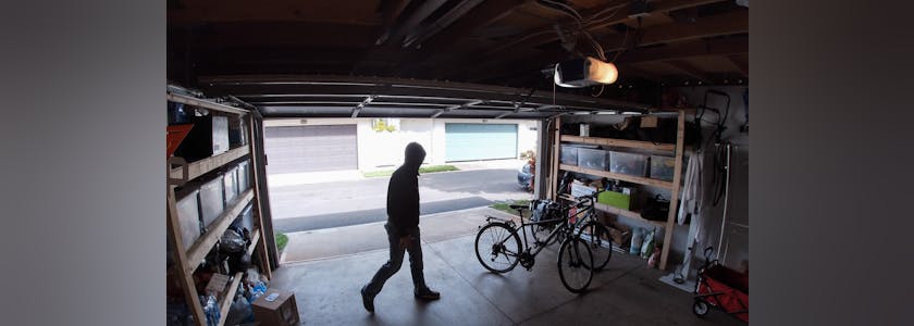 Person stealing bicycle from garage, surveillance camera view