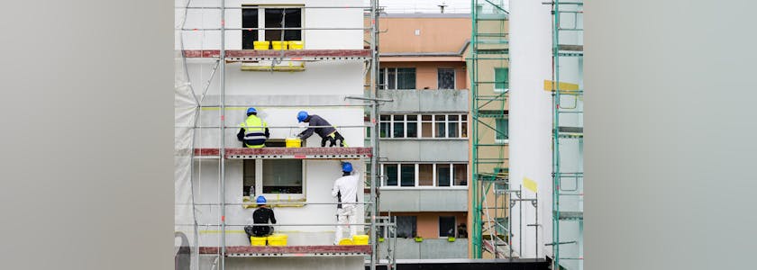 builders apply decorative plaster to the facade of the apartment house to be renovated