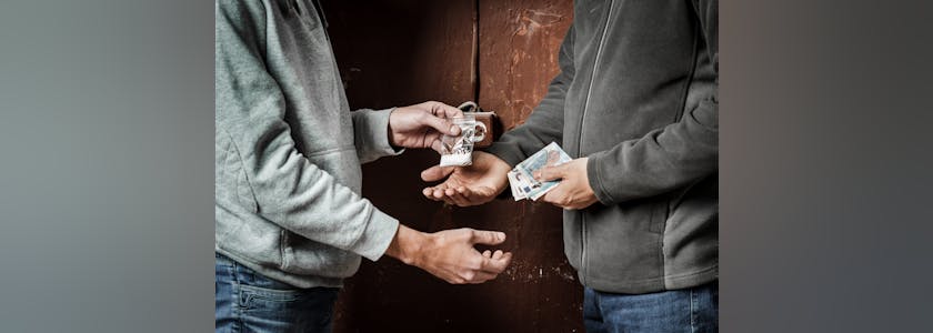 Hand of addict man with money buying dose of cocaine or heroine. Drug abuse and traffic concept