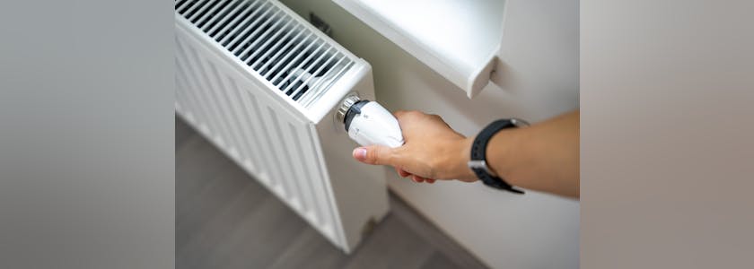 A woman’s hand turns the battery heating knob. Heating in an apartment, at home. Heating prices.
