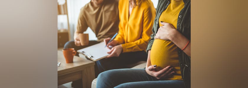 Future parents signing surrogacy agreement with expectant mother