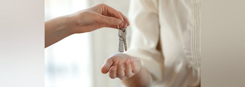 Close up young female realtor giving keys to happy buyer.
